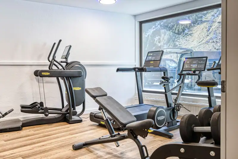 Treadmill, cross trainer and exercise bike in front of the large window with a view of the mountainside