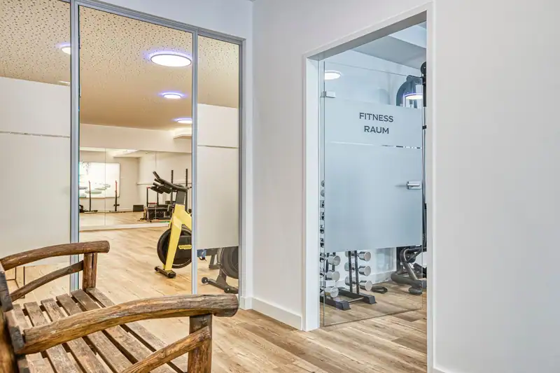 Entrance to the gym and FreiRaum with glass doors and a rustic wooden bench
