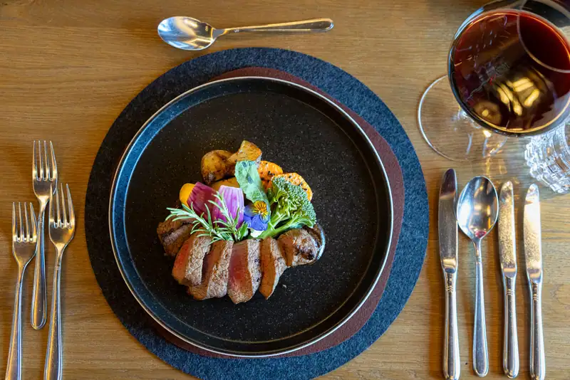Tender meat dish with sweet potato straw and red wine sauce on a slate plate