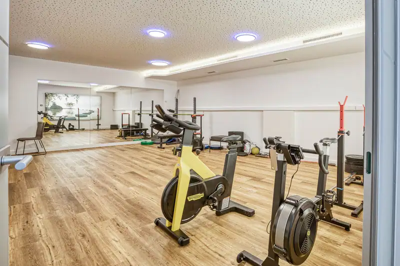 The FreiRaum with spinning bike, rowing machine, barbell racks and a large mirror wall