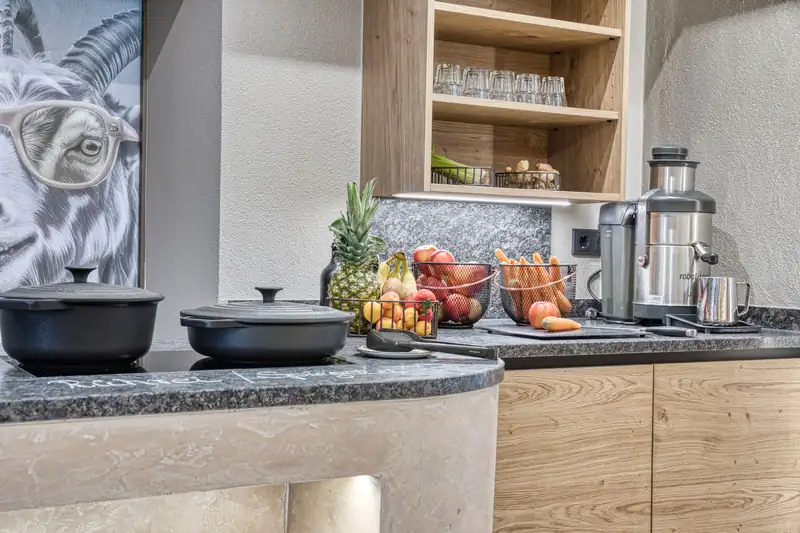 Egg station with black pots, fruit baskets, juicer and the ibex motif on the door behind