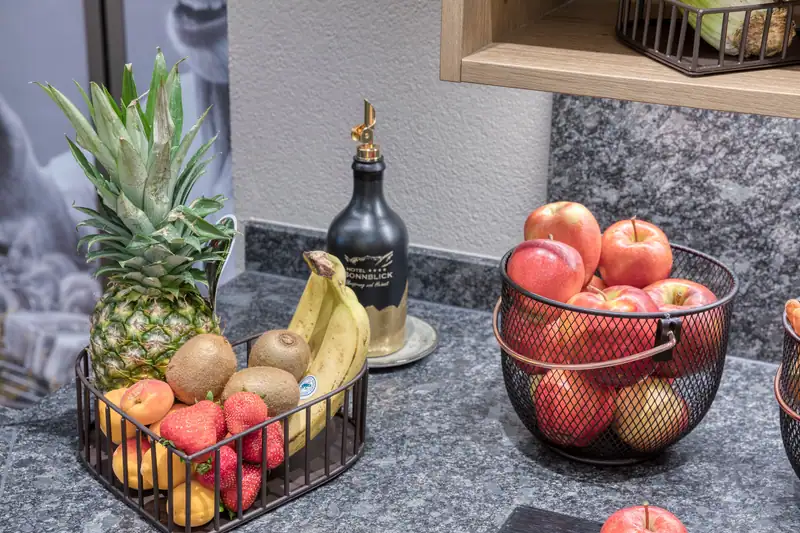 Fruit baskets with pineapple, bananas, kiwis, strawberries and red apples on the granite buffet