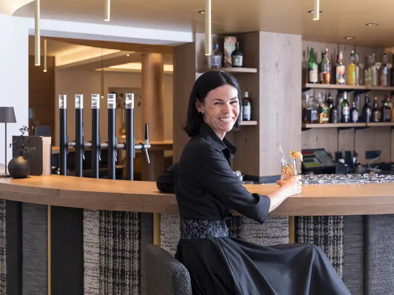 Hostess smiling at the hotel bar with a refreshing drink