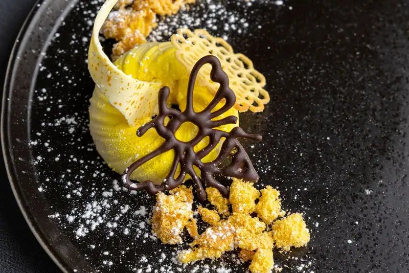 Yellow dessert with chocolate bee and tuile lattice