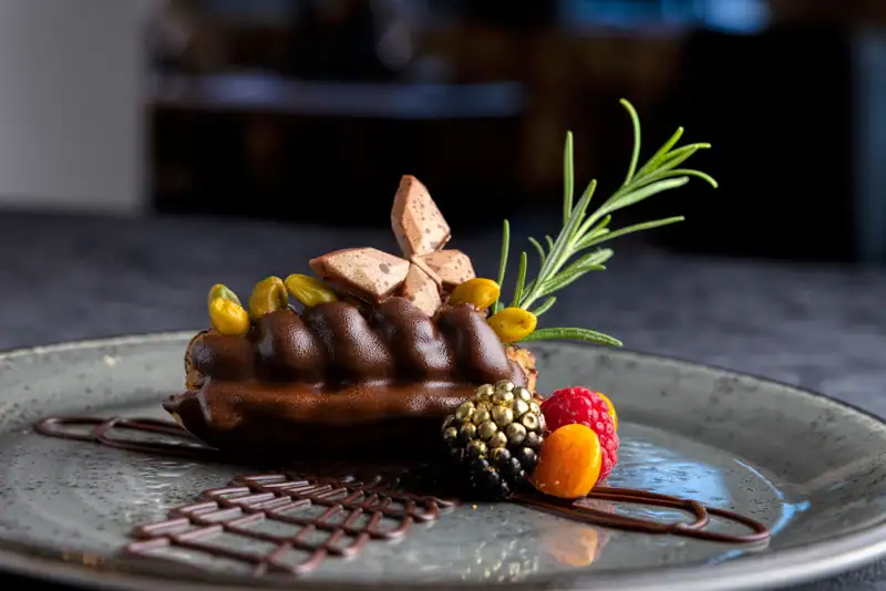 Chocolate dessert with pistachios, berries and chocolate lattice