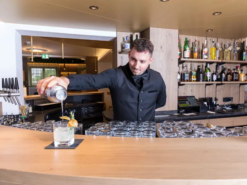 Bartender pouring a drink from the shaker into a glass