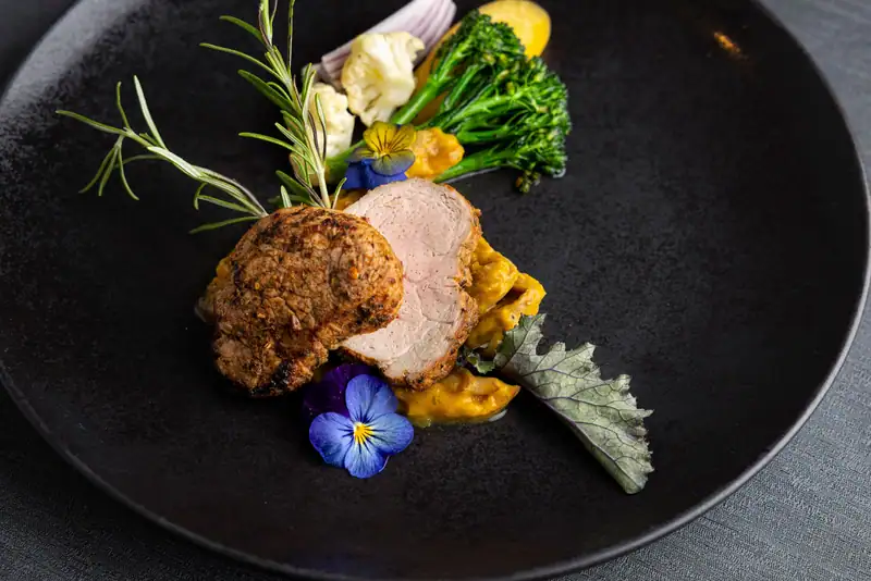 Sliced fillet with vegetables and blue horned violet, from above
