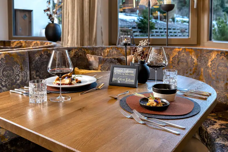 Laid table in the parlour with red wine glasses, candlelight and a handwritten welcome board