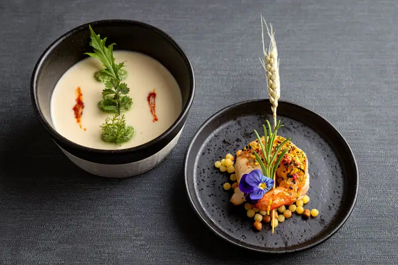 Cream soup with herb pesto and prawn on pearl couscous
