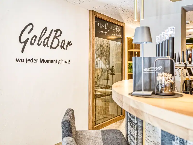 Lettering “GoldBar – wo jeder Moment glänzt!” (where every moment shines) on the wall next to the bar with a chalkboard