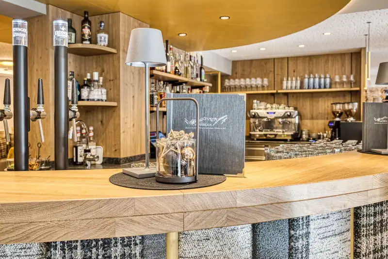Bar menu with Sonnblick logo, table lamp and decorative lantern on the wooden GoldBar counter