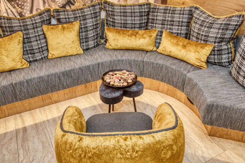 Round seating area with golden cushions and a plate of biscuits