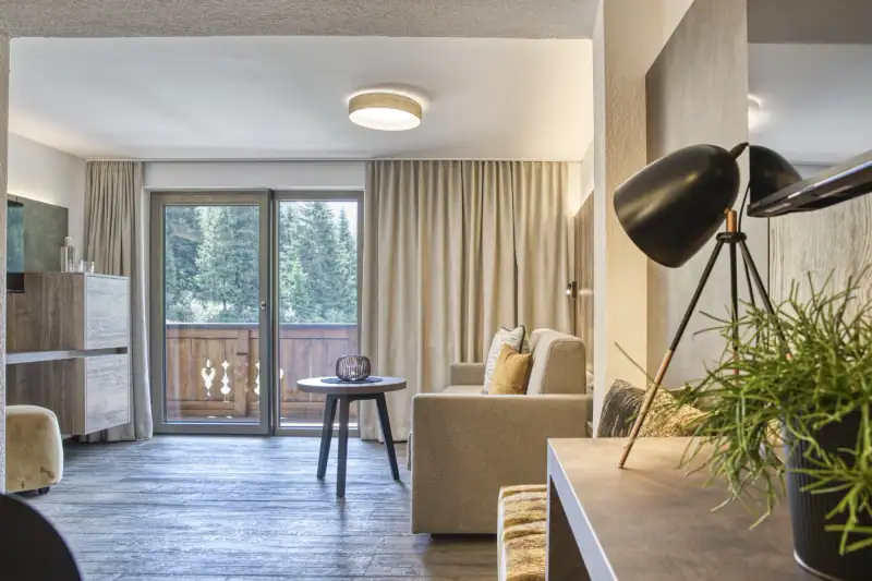 Neu gestalteter Wohnbereich mit Schlafsofa, rundem Beistelltisch und Balkontür mit Blick in den Wald