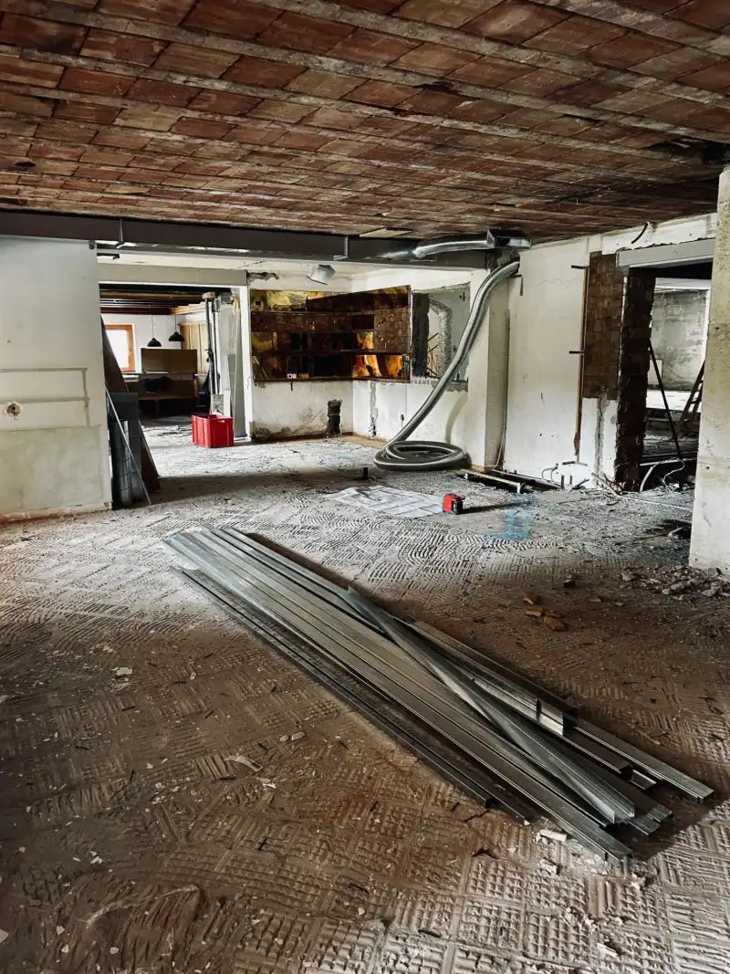 Die alte Bar im Abriss: offener Raum mit freigelegter Decke, Lüftungsschlauch und Metallprofilen am Boden