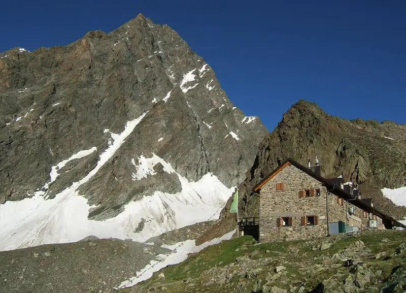 Natural stone Kaunergrat hut beneath the steep rock and snowfield of the Kaunergrat