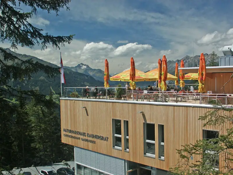 Kaunergrat nature park house with wooden facade and sun terrace above the valley, mountains behind
