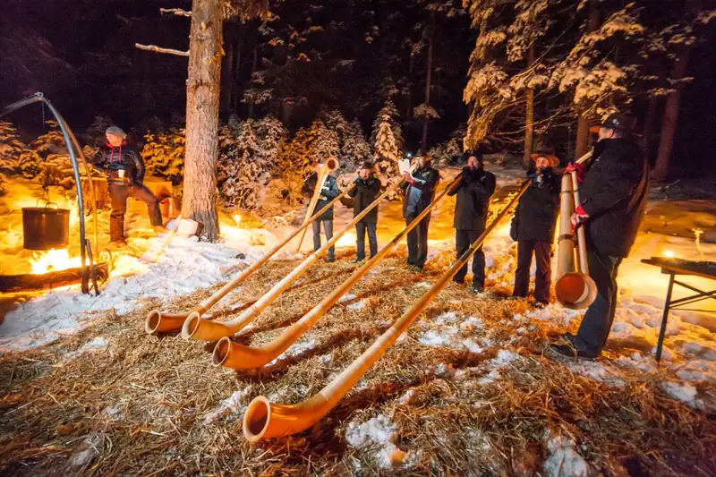 Alphorn players at a campfire in the snowy forest