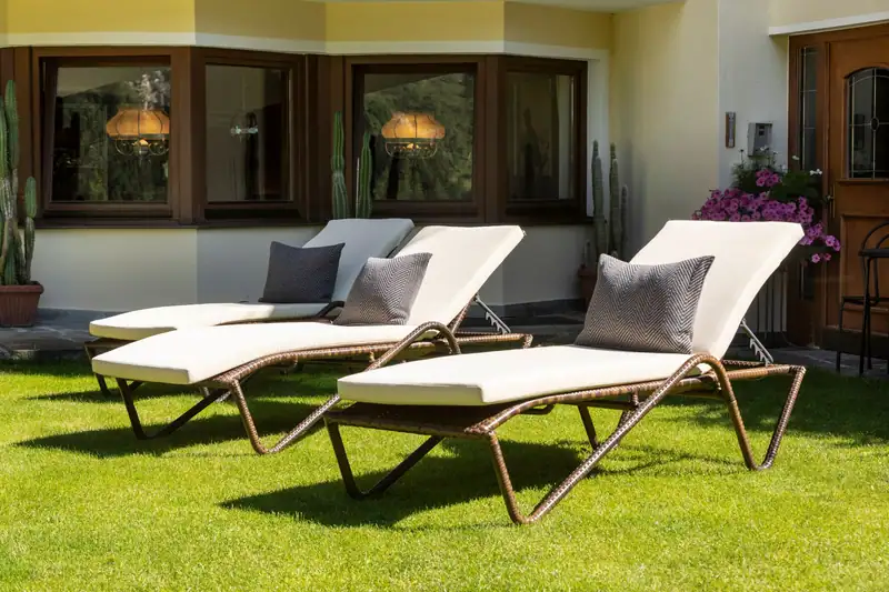 Three garden loungers with white cushions on the lawn in front of the hotel