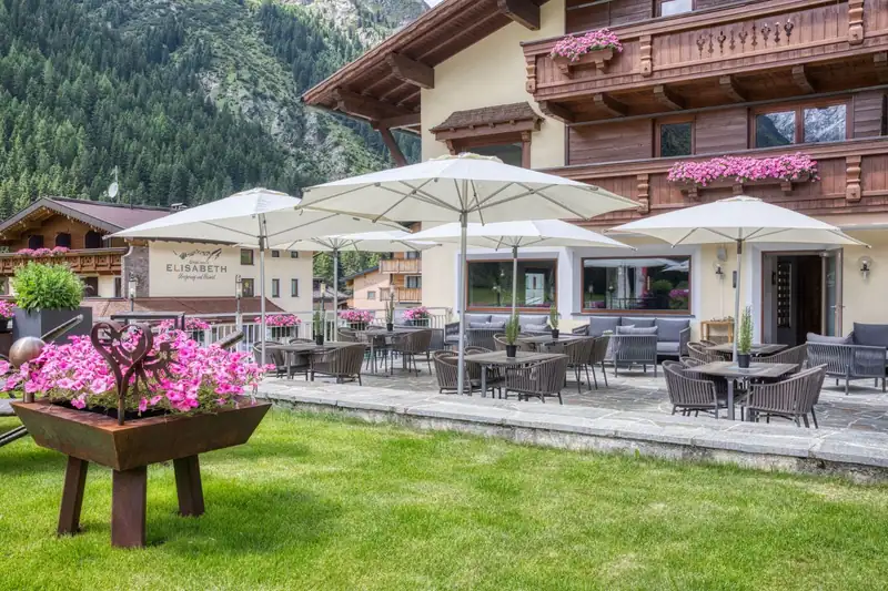 Sun terrace with white umbrellas and flowers, B&B Elisabeth in the background