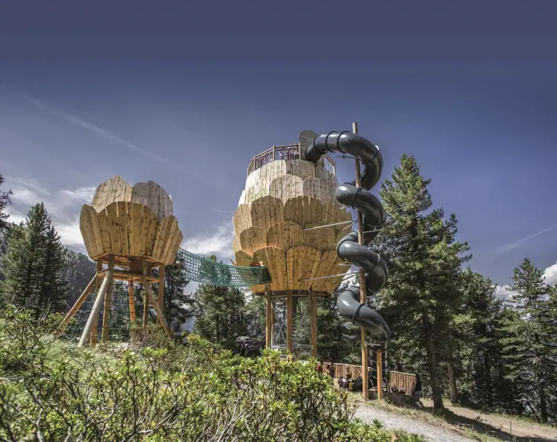 Wooden pine cone adventure tower with suspension bridge and tube slide in the ZirbenPark on the Hochzeiger