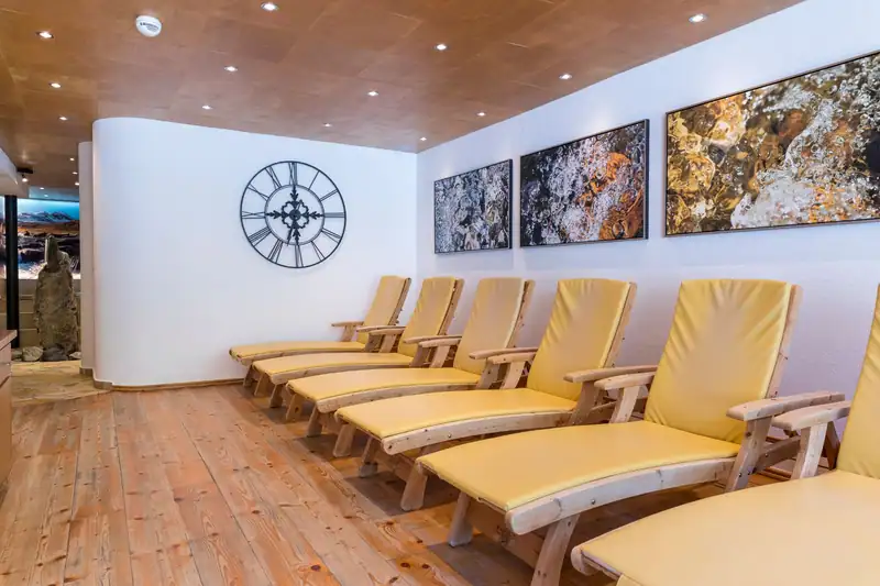 Relaxation room with yellow wooden loungers, a large wall clock and water pictures