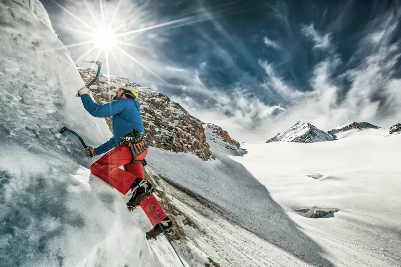 Ice climber with axes on an ice wall at the glacier, sun in backlight