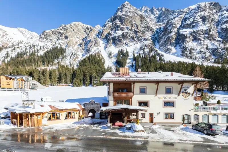 Entrance of Hotel Sonnblick in winter in front of rugged, snowy rock peaks