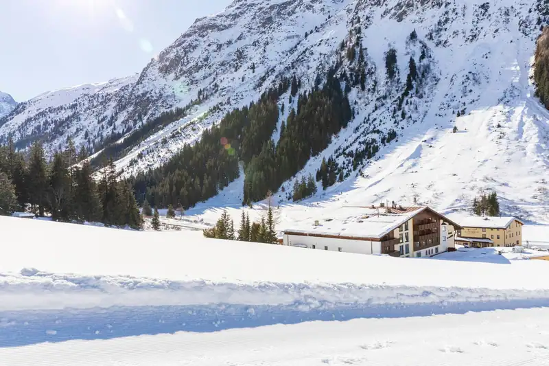Freshly groomed cross-country trail in front of the snowy Hotel Sonnblick and B&B Elisabeth