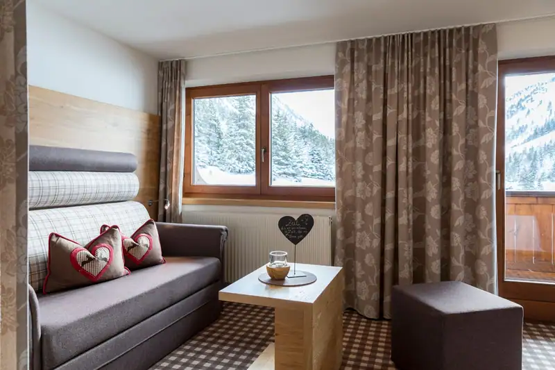 Living area with sofa bed, stool and balcony door with mountain view