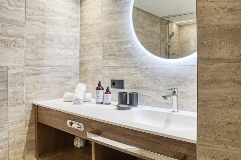 Bathroom with wooden washbasin and round illuminated mirror