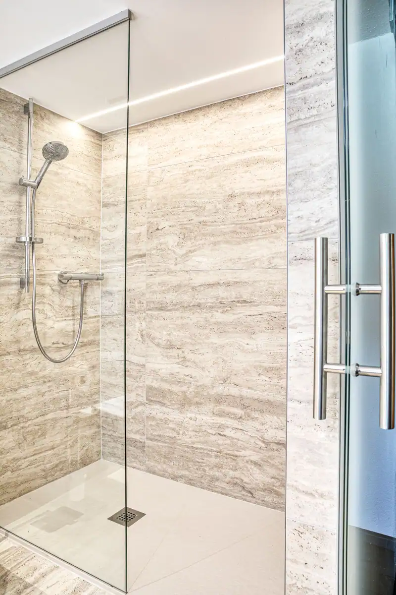 Walk-in shower with glass wall and natural stone look