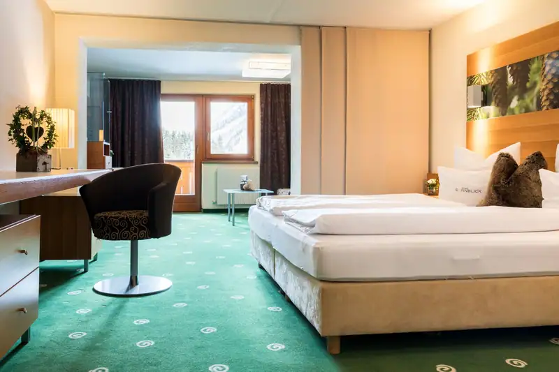 Panorama Suite with box-spring bed, desk, living area and balcony door
