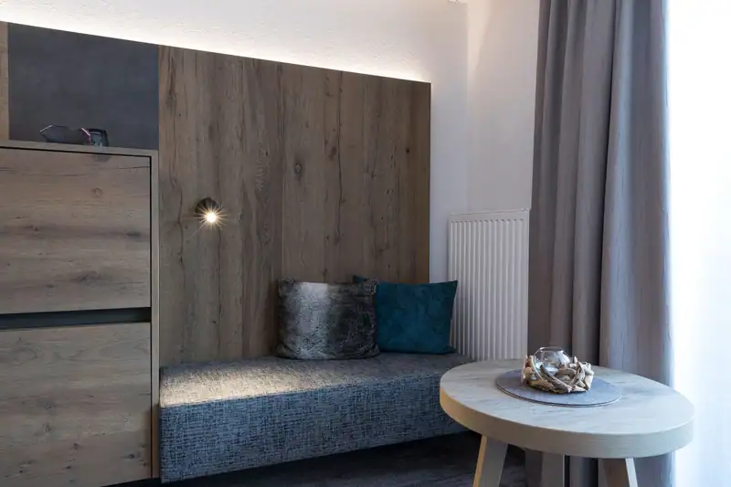 Upholstered bench seat with cushions in front of the wooden wall and round side table