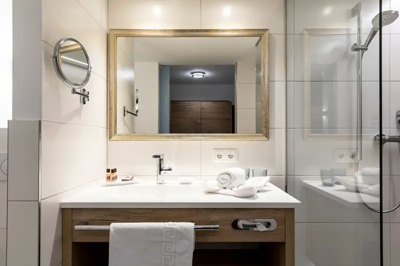 Wooden washbasin with gold-framed mirror and make-up mirror