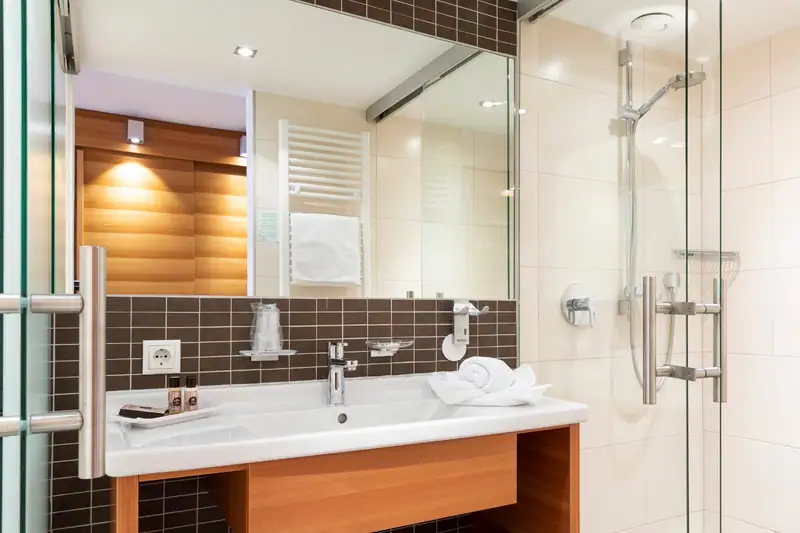 Bathroom with washbasin, large mirror and shower with glass door