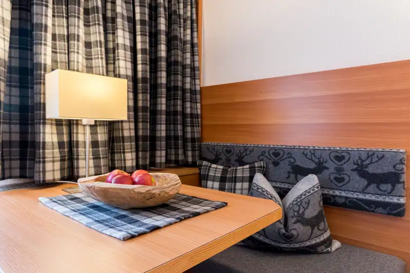 Wooden bowl with apples on the table, behind it a table lamp and bench seat