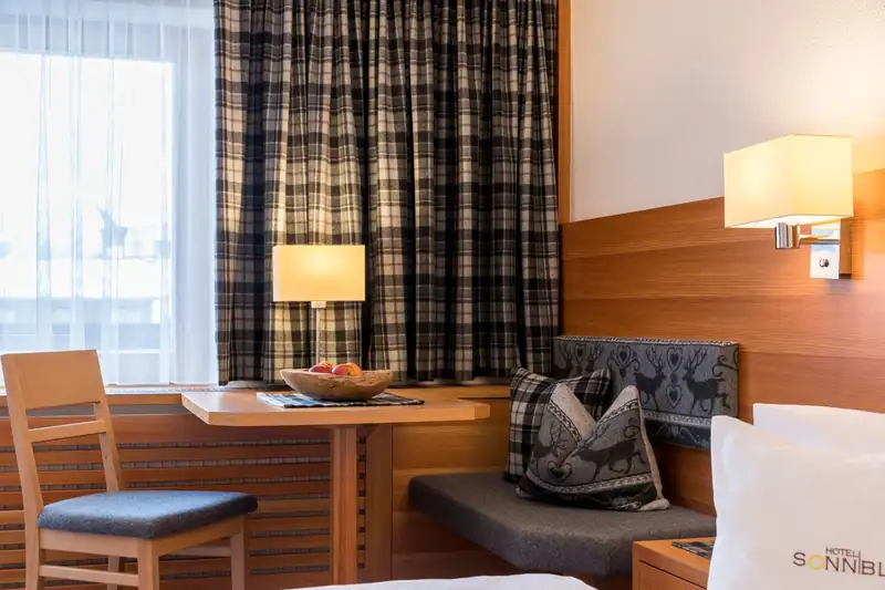Bench seat with deer motif, table and chair by the window with checked curtains